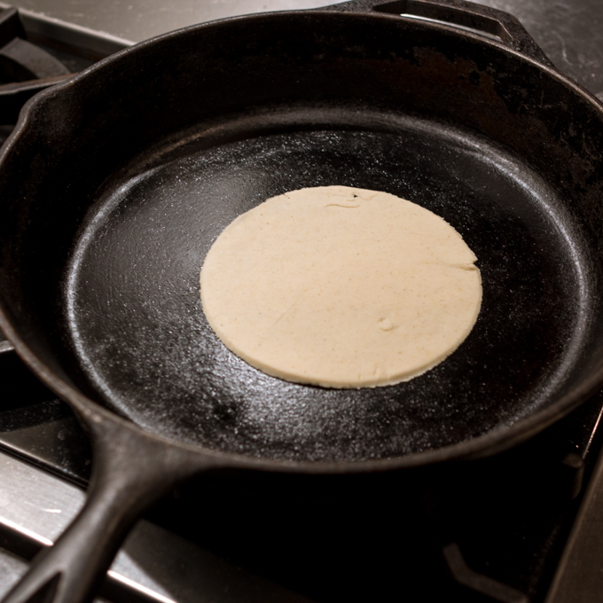 oiled iron skillet cooking tortilla